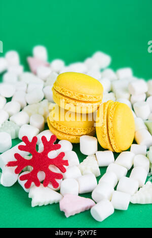 Yellow macaroons, marshmallow and red flake on green Stock Photo