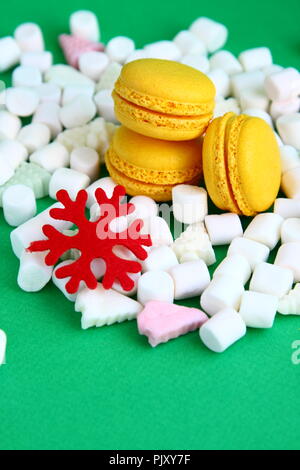 Yellow macaroons, marshmallow and red flake on green Stock Photo