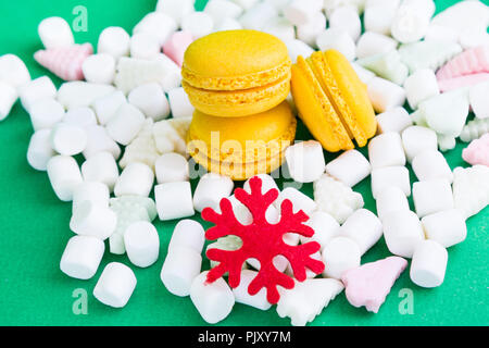 Yellow macaroons, marshmallow and red flake on green Stock Photo
