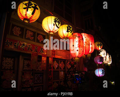 Red and yellow traditional chinese lanterns and sticker on an exterior wall. Shennong Street lluminated by chinese lanterns. Tainan, Taiwan Stock Photo