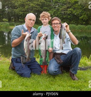 Three generation of fishermen at Meon Springs Trout Fishery, Hampshire, England, United Kingdom. Stock Photo