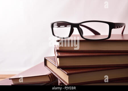 Glasses on stack of books with white background. Concept need glasses to read. Front view. Horizontal composition Stock Photo