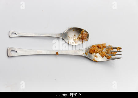 A close up view of adirty silver small spoon and fork next to each other on a isolated white background Stock Photo