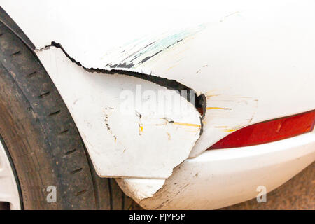 A close up side view of damaged done to the bottom fender on a white car Stock Photo