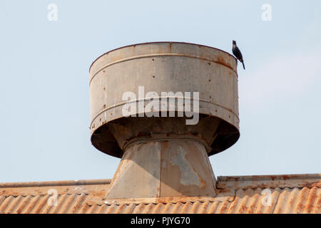 A close up of a metal air vents on a rusted old steel roof of an abandened buiding Stock Photo