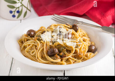 Pasta with black olives and anchovies on rustic white table Stock Photo