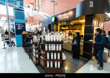 Japan, Osaka. Kansai International Airport. KIX, Interior terminal one, ground floor arrival area. Starbucks coffee shop with people at counter. Stock Photo