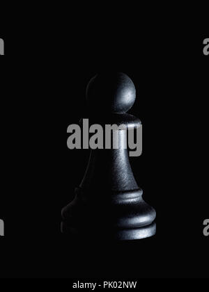 Single black chess piece pawn on black, dramatic lighting. Manipulation, powerlessness, hidden victim concept. Stock Photo