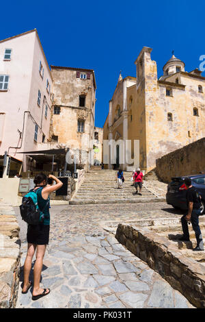 Tourist taking photograph of Saint-Jean Baptiste cathedral in Calvi citadel, Corsica, France Stock Photo