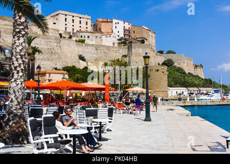 Waterfront restaurants, citadel in background. Calvi, Corsica, France Stock Photo