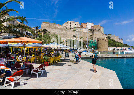 Waterfront restaurants, citadel in background. Calvi, Corsica, France Stock Photo