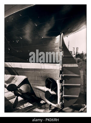 TITANIC STERN WORKER SIZE CONSTRUCTION Historic 1912 image of RMS Titanic rudder and propellors with ship worker in the huge dry dock construction site adding scale to the huge Ocean Liner Harland and Wolff shipyard Belfast UK Stock Photo