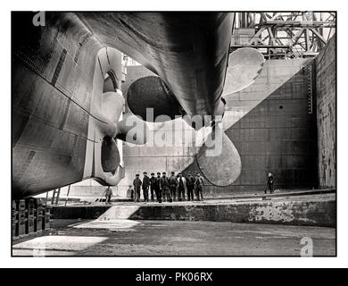 TITANIC/OLYMPIC PROPELLOR  Historic ship build 1912 image of RMS Titanic rudder and propellors with group of ship workers in the huge dry dock construction site adding scale to the huge Ocean Liner. Harland and Wolff shipyard Belfast UK Stock Photo