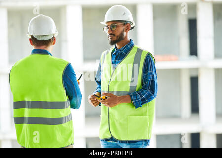 Confident worker listening to colleagues at apartment block site Stock Photo