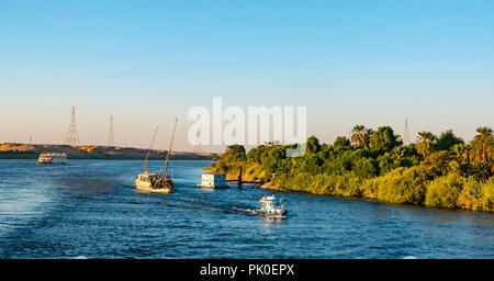 Tug pulling tourist sailing cruise boat up river in late afternoon sun, Nile River, Egypt, Africa Stock Photo