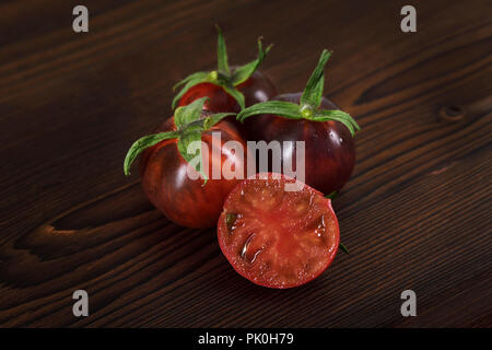 Indigo Rose organic tomatoes with deep red color and rich flavour, anti-cancer, rich in antioxidants and anthocyanins. Artistic still life on dark woo Stock Photo