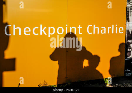 Shadows of tourists reflect on Billboards at the Checkpoint Charlie Museum in Berlin, Germany Stock Photo