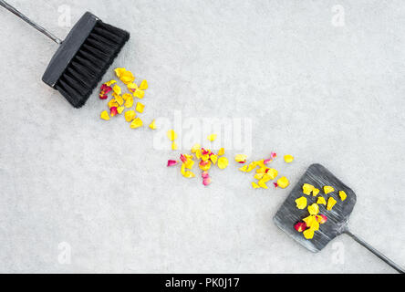 Yellow rose petals, black brush and iron dustpan, on concrete floor background. Change of seasons concept. Stock Photo