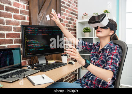 young female touching air by wearing virtual reality goggles in a future technology way. Stock Photo