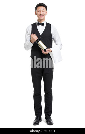 Cheerful young Chinese waiter holding a bottle of red wine Stock Photo