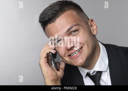 Close-up portrait of a smiling elegant young businessman using cellphone Stock Photo