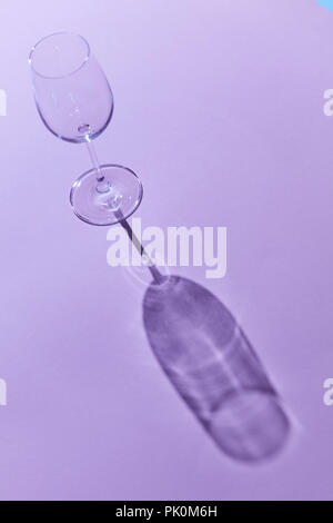 A glass of wine on a purple background with a falling shadow from a glass Stock Photo