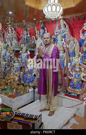 A Hindu pandit worshipping in a small temple in the basement of his home where he leads a congregation. In South Richmond Hill, Queens, New York. Stock Photo