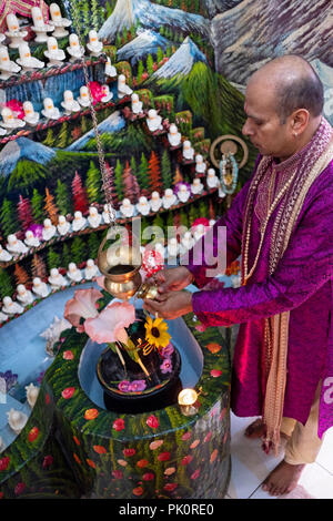 A Hindu pandit worshipping in a small temple in the basement of his home where he lead a congregation. In South Richmond Hill, Queens, New York. Stock Photo