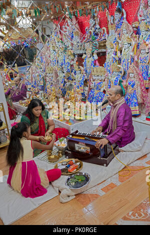 A Hindu pandit conducting a prayer service in a small temple in the basement of his home in South Richmond Hill, Queens, New York. Stock Photo