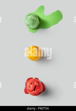 Various scoops of delicious melting ice cream with splashes on a gray concrete background. Copy space for text. Top view Stock Photo