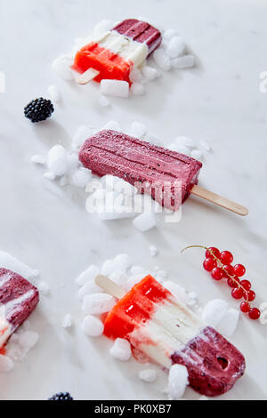 Colorful fruit popsicles with crushed ice and berries over marble background. Summer food concept Stock Photo