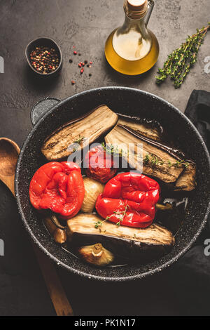 Oven roasted vegetables on pan. Roasted eggplant, red bell pepper, onion, garlic and tomato. Healthy vegetarian food. Top view, toned image Stock Photo