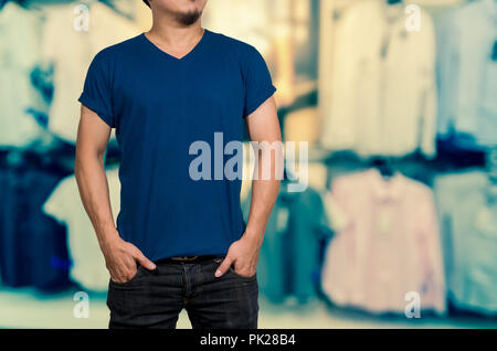Man wearing blank t-shirt on Abstract blurred photo of clothing store in a shopping mall, shopping concept Stock Photo