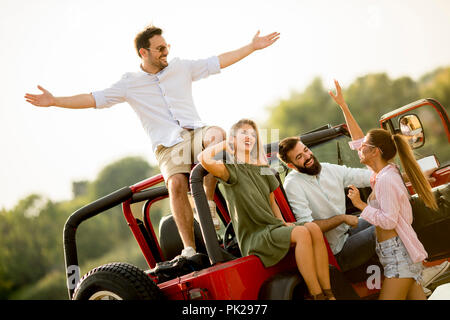 Happy friends having fun in convertible car at vacation by river Stock Photo