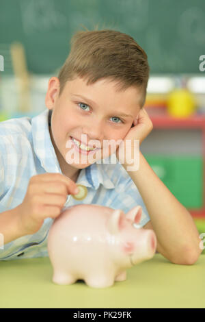 boy putting a coin in a piggy bank Stock Photo