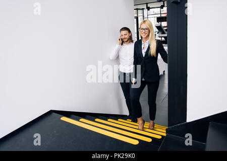 Young business couple with mobile phone on the stairs in office Stock Photo