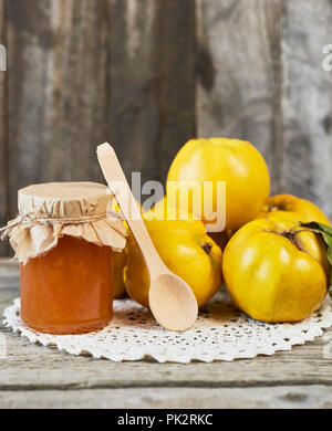 jar of jam and quinces with leaves on wooden rustic background Stock Photo