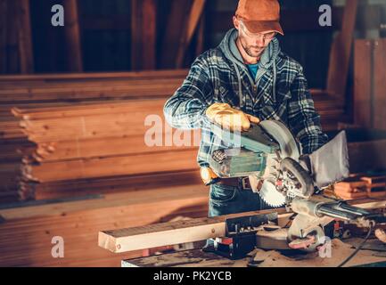 Woodwork Contractor Job. Caucasian Worker Cutting Wood Planks Using Circular Wood Saw. Construction Industry. Stock Photo