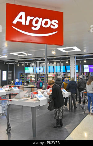 Shopping customers in new Argos catalogue shop inside a Sainsburys supermarket store replacing & closing down local high street premises England UK Stock Photo