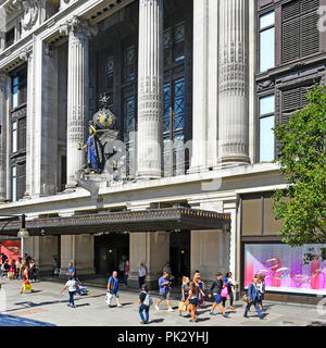 Shoppers in London shopping street scene front exterior façade & sculpture at Selfridges Oxford Street department store building West End Mayfair UK Stock Photo