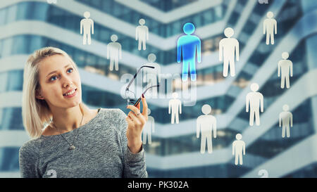 Smiling woman holding glasses and thinking about staff choice. Choosing a different person from the crowd. Employee selection, group leadership concep Stock Photo