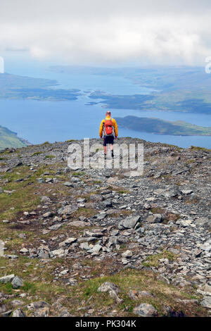 Walker descending Ben More on Mull with views of Loch Na Keal with the island of Eorsa and beyond the narrows between Ulva on the left and Mull Stock Photo