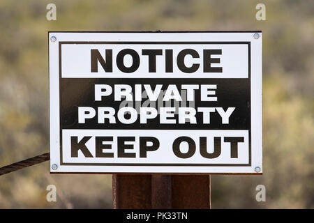 Weathered generic private property keep out sign on rusty metal fence post. Stock Photo