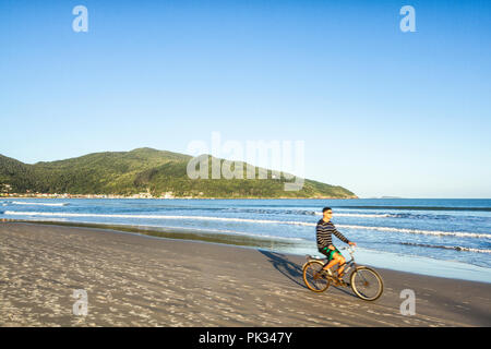 Man riding a bicycle at Acores Beach. Florianopolis, Santa Catarina, Brazil. Stock Photo