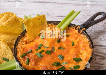 Buffalo chicken dip in an iron skillet with chips and celery Stock Photo