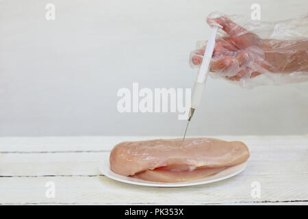 People make injection syringe in chicken fillet on white background. Stock Photo