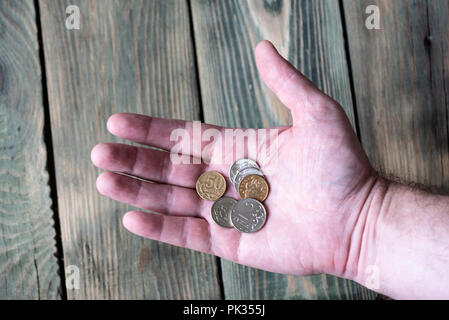 Several Russian metal rubles lie in a man's hand over a wooden t Stock Photo