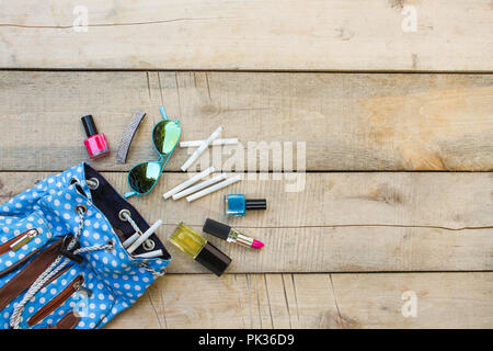 Cosmetics and cigarettes fell out of the backpack of a teenager on a wooden background. Top view. Flat lay. Stock Photo