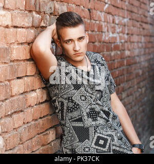 Portrait of a stylish handsome guy from America. Standing near red brick wall. Stock Photo