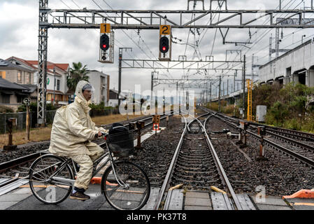 TOKYO, JAPAN - NOVEMBER 20, 2015: Young Japanese student is passing the railway by bicycle in Tokyo, Japan. Stock Photo